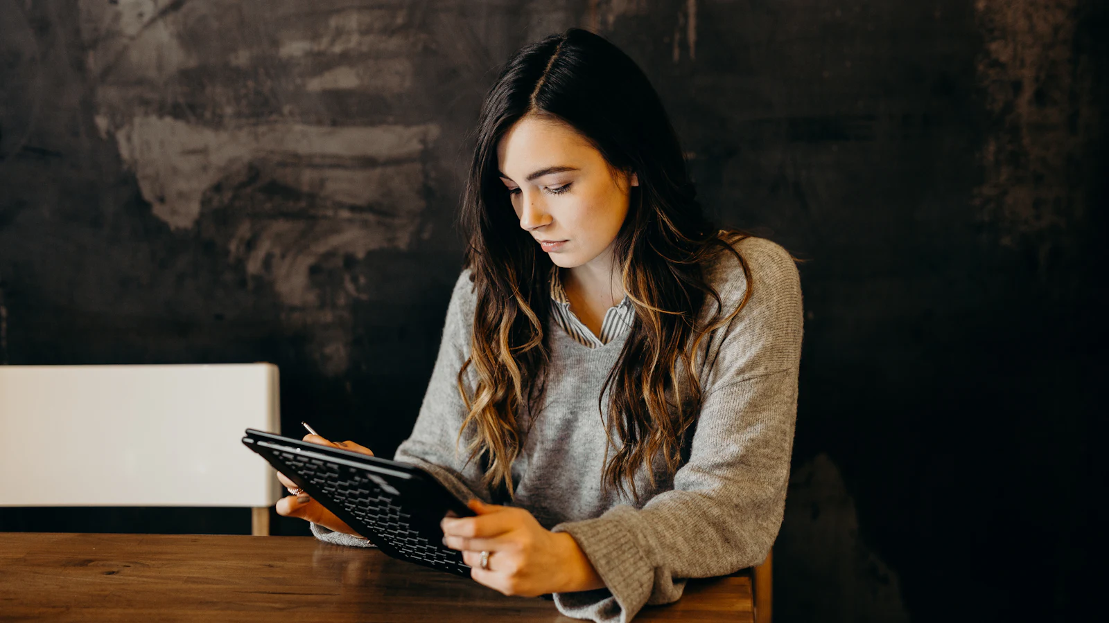 Woman reading on a tablet at a wooden table