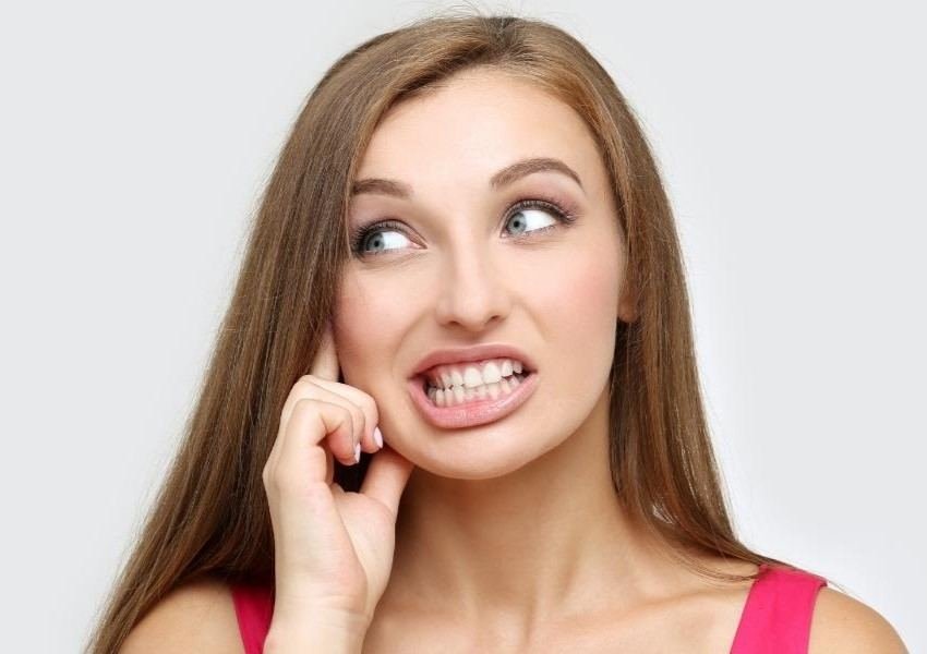 A woman looking uncertain about her smile, representing common worries about dental tourism
